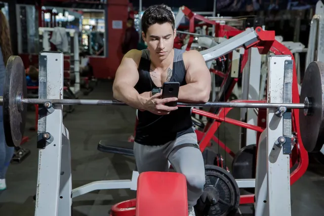Gym-goer checking his phone between sets