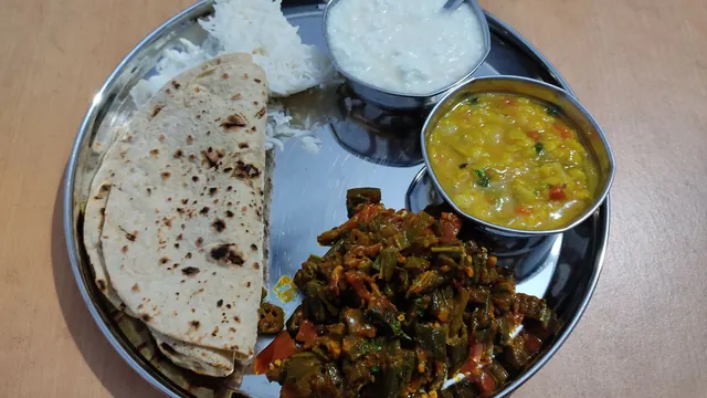 A steel thali with chapati, rice, dal, curd and bhindi
