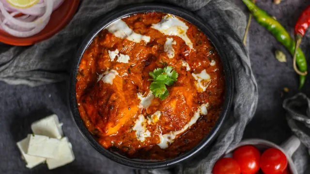 A paneer curry served in a black ceramic bowl