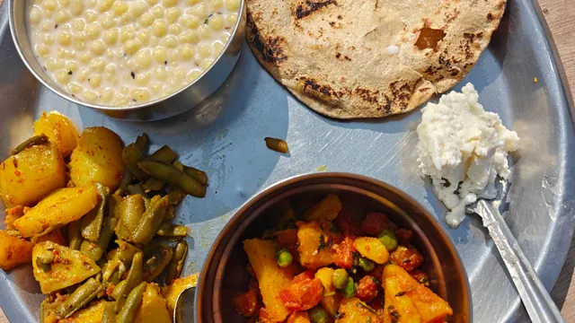 An Indian thali with roti, sabzi and dal on a steel plate